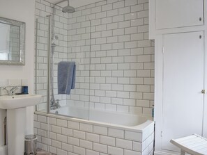 A bathroom with a white tiled shower, a bathtub, a sink, and a mirror.