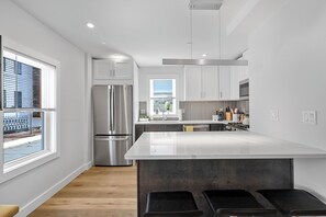 A modern kitchen with white cabinets, stainless steel appliances, and a large island.