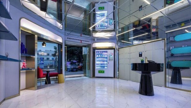 A modern interior with a glass wall, a vending machine, and a seating area. - 100 Inn (Shanghai Hongqiao Airport National Exhibition and Convention Center) (Shanghai)