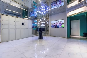 A lobby with a marble floor, lockers, a reception desk, and a wall-mounted TV screen. - 100 Inn (Shanghai Hongqiao Airport National Exhibition and Convention Center) (Shanghai)