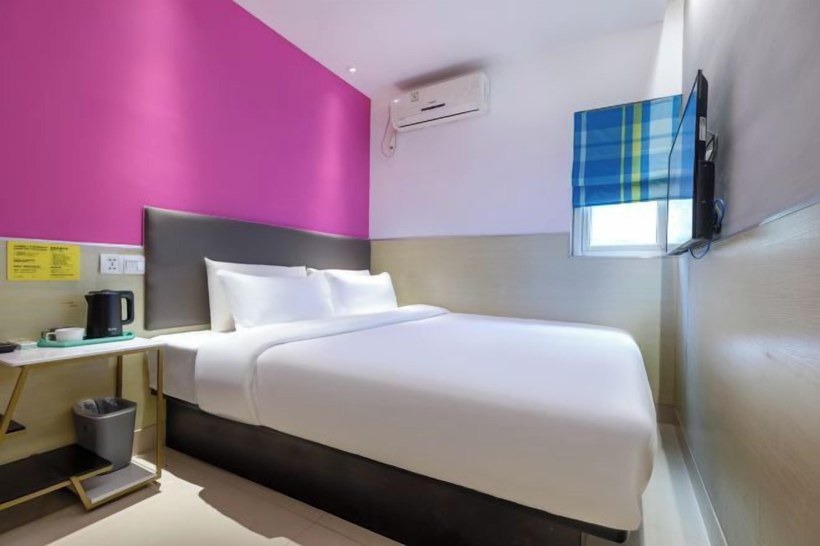 A hotel room with a bed, bedside table, and a window with a view.