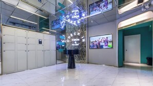 A modern lobby with lockers, a check-in counter, and digital screens displaying images. - 100 Inn (Shanghai Hongqiao Airport National Exhibition and Convention Center) (Shanghai)