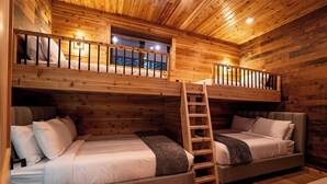 A cabin-style bedroom with two beds, a loft bed, and a wooden ladder. - Cozy Mountain Getaway with Hot Tub  Sleeps Your Whole Group (Revelstoke)