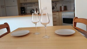 A dining table with two wine glasses and two plates, set in a kitchen with wooden cabinets and a white countertop. - Yellow mountain in paradise (Costa del Silencio)