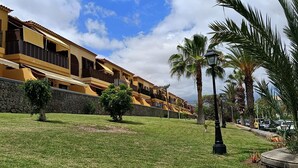 A hotel with a yellow facade, multiple balconies, and a stone wall. - Yellow mountain in paradise (Costa del Silencio)