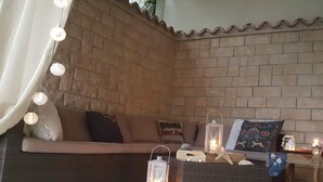 A cozy corner with a cushioned bench, wicker furniture, and decorative lanterns.