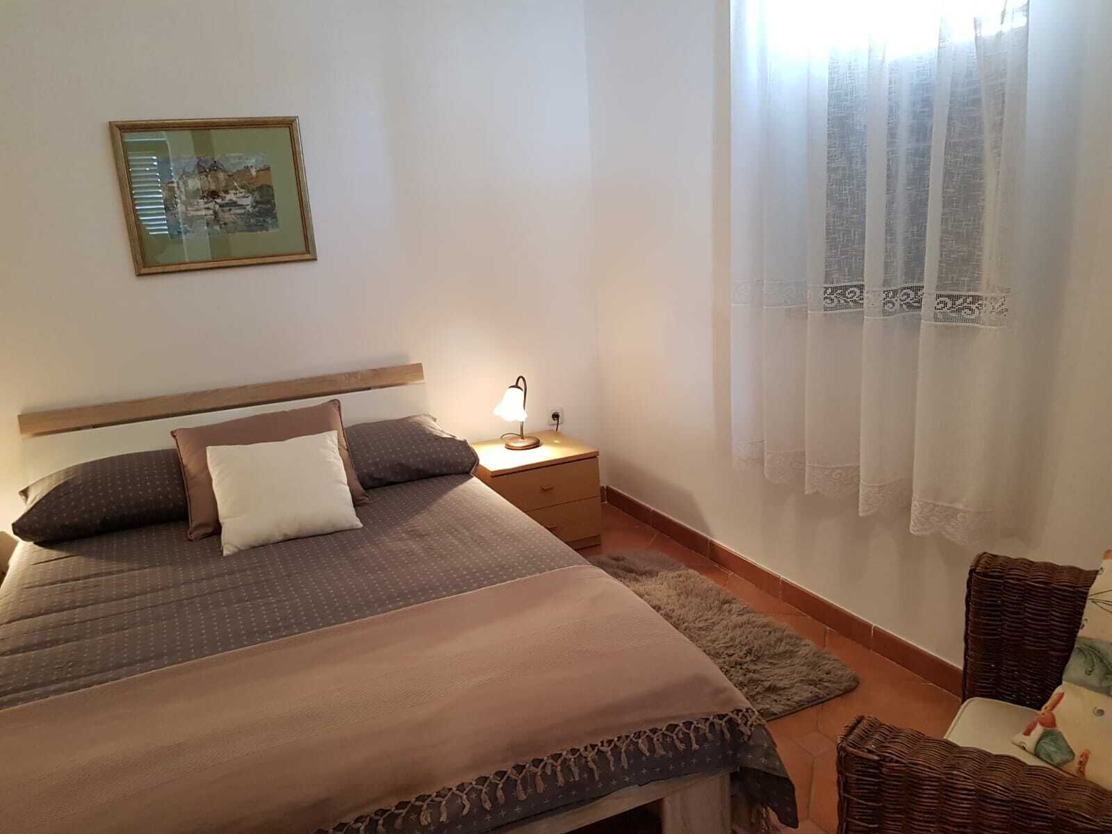 A bedroom with a bed, nightstand, lamp, and curtains.