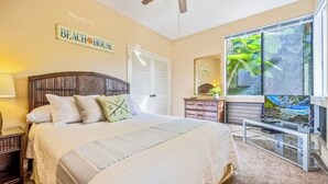 A bedroom with a large bed, a TV, a window with a view of greenery, and a sign that says "Beach House". - Spacious 3BR/2BA Condo in Wailea – Walk to Beach & Shops! (Wailea-Makena)