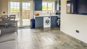 A modern kitchen with grey cabinets, a washing machine, and a large window.