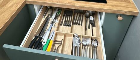 Una cocina con estufa integrada, cafetera y organizador de cajones con utensilios.