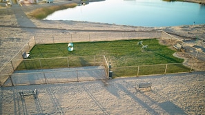 A fenced area with a grassy field, a metal structure, and benches.