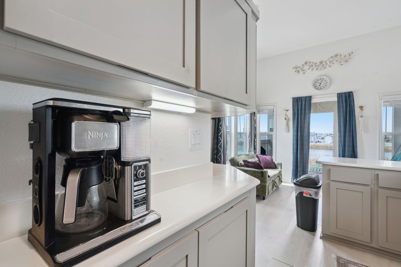 Una cocina moderna con una cafetera NINJA, una ventana con cortinas y vistas al exterior.