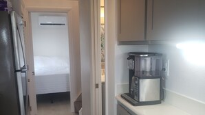 Cocina pequeña y estrecha con un refrigerador, microondas y cafetera en la encimera.