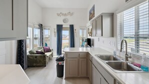 A compact kitchen with a central island, a built-in oven, and a window with blinds.
