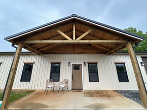 A building with a covered porch, two chairs, and a 'hello' mat.