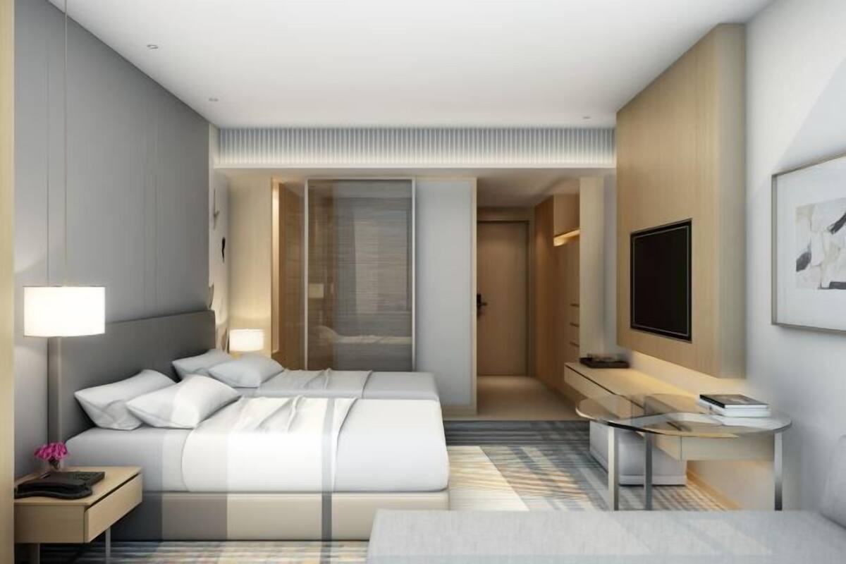 Ein modernes Hotelzimmer mit einem großen Bett, Nachttischen, einem Schreibtisch und einem Fernseher.