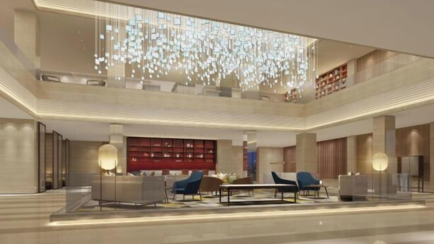 Un hall d’entrée spacieux avec un plafond haut, un espace salon central et un grand mur décoratif illuminé.