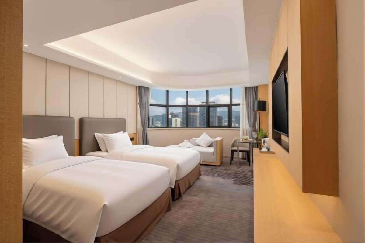 Une chambre d’hôtel avec deux lits, un bureau, une chaise, une télévision et une vue sur la ville.