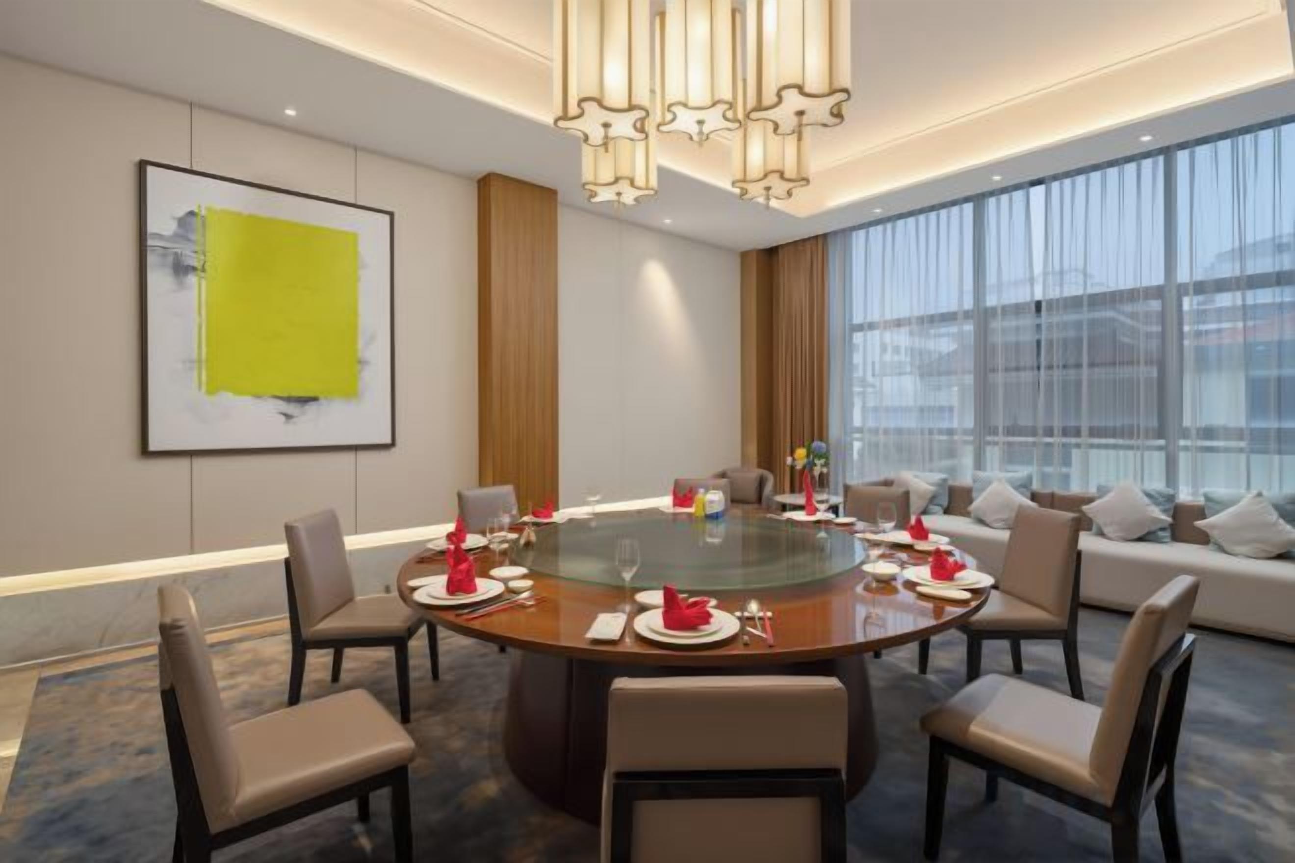 A modern conference room with a glass table, comfortable seating, and a large window providing a view.