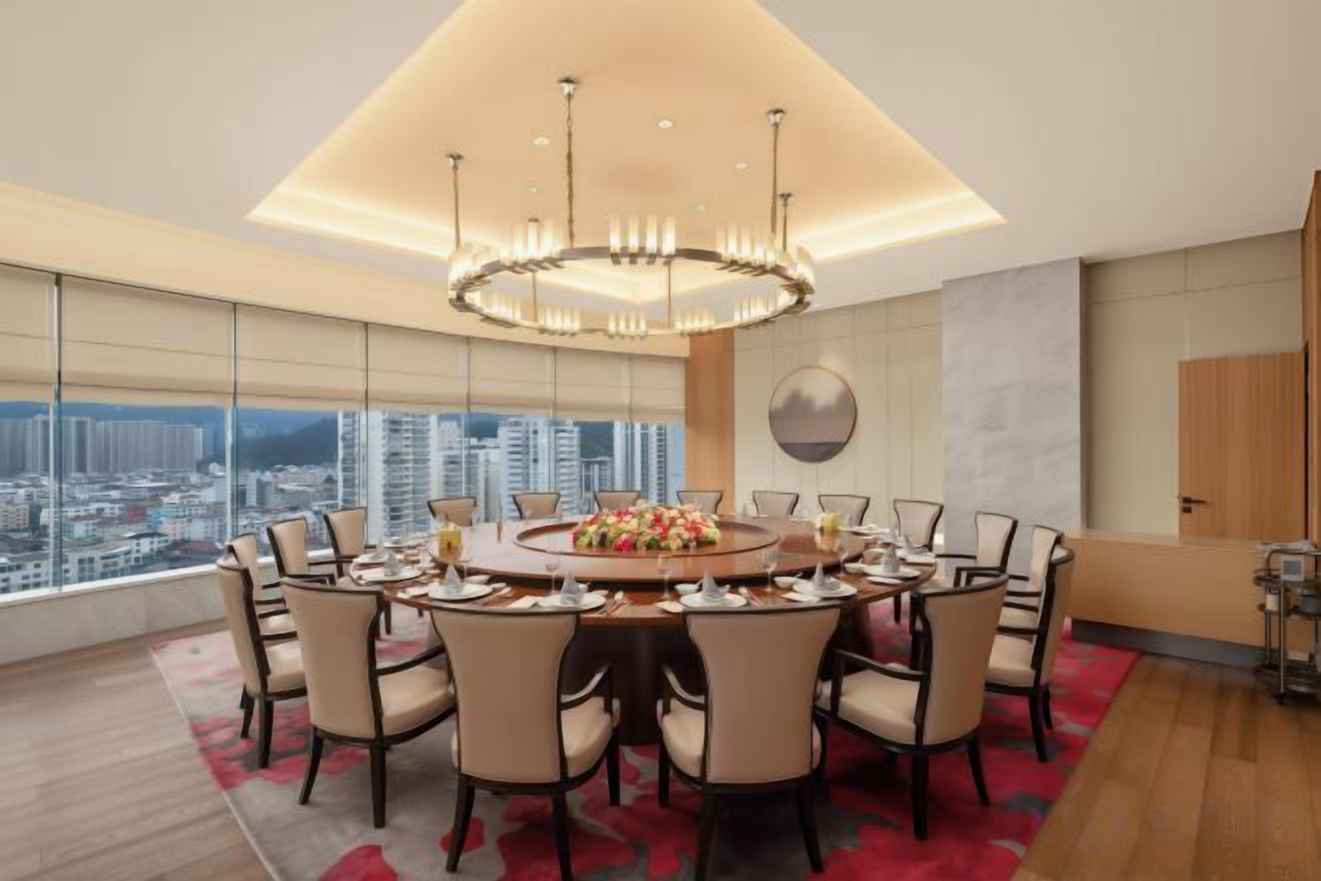 A modern dining room with a round table, chairs, and a chandelier.
