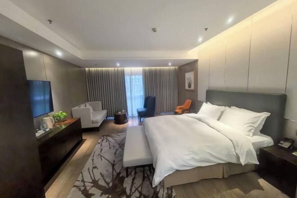 Ein modernes Hotelzimmer mit einem großen Bett, einer Couch, einem Schreibtisch und einem Fernseher.