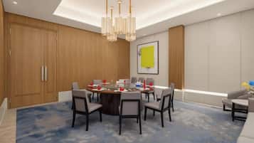 A conference room with a round table, chairs, a chandelier, and a blue carpet.