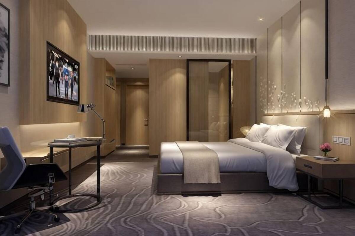 Ein modernes Hotelzimmer mit einem großen Bett, Nachttischen, einem Schreibtisch und einem Sessel.