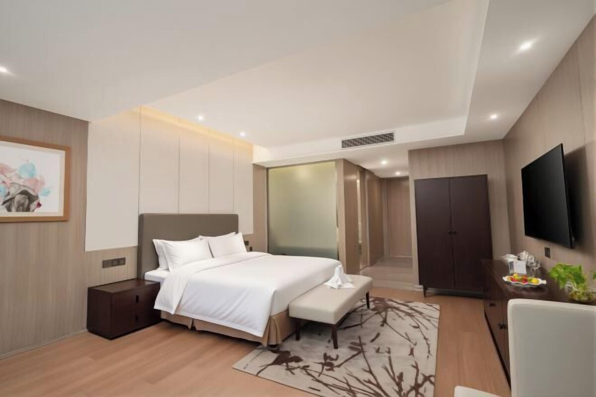 Une chambre moderne avec un grand lit, des tables de chevet, un téléviseur à écran plat et un dressing.