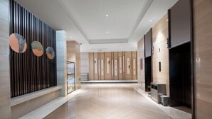 Un hall d’entrée spacieux doté d’un plancher en bois poli, d’un comptoir d’accueil moderne et d’un mur orné d’œuvres d’art abstraites.