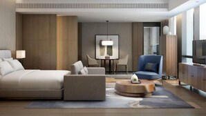 Une chambre d’hôtel moderne dotée d’un grand lit, d’un canapé, d’une table basse, d’une télévision et d’un coin repas avec des chaises et une table.