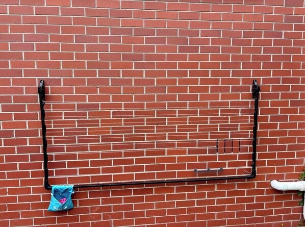 A red brick wall with a black metal rack and a blue bag hanging on it.