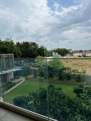 A modern building with a glass balcony overlooking a well-maintained garden and a residential area. - RT properties at the Lennox  (Accra)