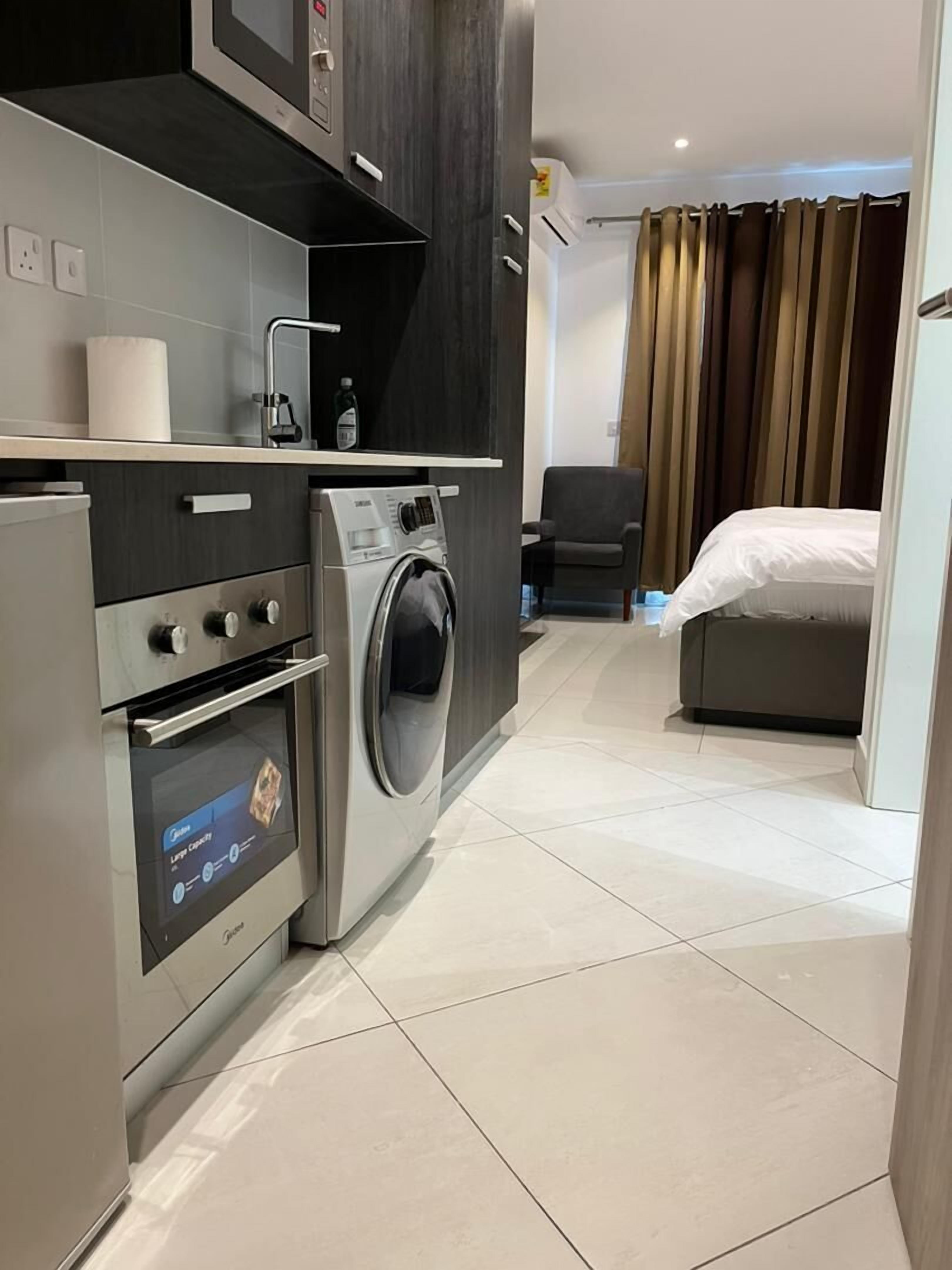 Habitación de hotel compacta con kitchenette, que incluye microondas, horno y lavadora.