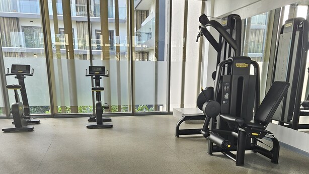 A gym with exercise equipment, large windows, and a black rubber floor. - RT properties at the Lennox  (Accra)