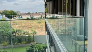 A modern apartment with a balcony overlooking a landscaped garden and distant buildings. - RT properties at the Lennox  (Accra)