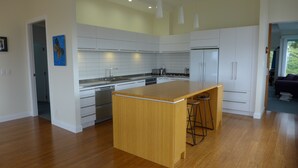 Una cocina moderna con armarios blancos, una isla de madera y electrodomésticos de acero inoxidable.
