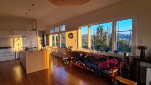 Una cocina amplia con una isla central, ventanas grandes con vistas al exterior y una zona de estar acogedora con un sofá y sillones.