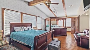 Ein Schlafzimmer mit einem großen Bett, einer Holzbalkendecke und einem Deckenventilator.