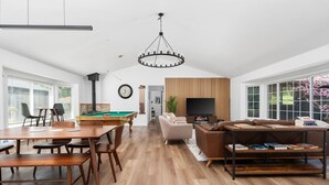 Amplia sala de estar con mesa de billar, sofá, televisión y estantería.