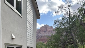A house with a patio area, a barbecue grill, and a view of a mountain range.