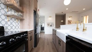A modern kitchen with black appliances, wooden cabinets, and a white countertop. - Primrose Cottage at Zion (Springdale)