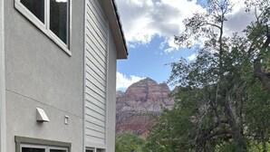 Una casa con patio, una parrilla y vistas a una cordillera.