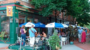 An outdoor seating area with tables and chairs, a green awning, and a brick building with a sign reading "RESTAURANT & BREWERY". - Hip Suite-1st Floor - Arts District/Farmers Mkt/Cafes/Breweries-Near Lake George (Glens Falls)
