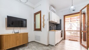 A modern kitchen with a built-in oven, a wooden cabinet, and a flat-screen TV. - Gigi's House – Comfort & Relax (Villasimius)