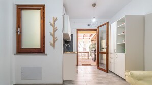A modern kitchen with a wooden-framed window, a built-in stove, and a dining area visible through an open door. - Gigi's House – Comfort & Relax (Villasimius)