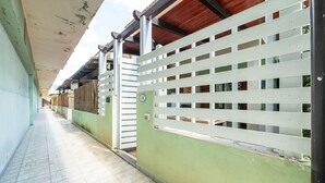 A corridor with a tiled floor, a green wall, and a white fence with horizontal slats. - Gigi's House – Comfort & Relax (Villasimius)