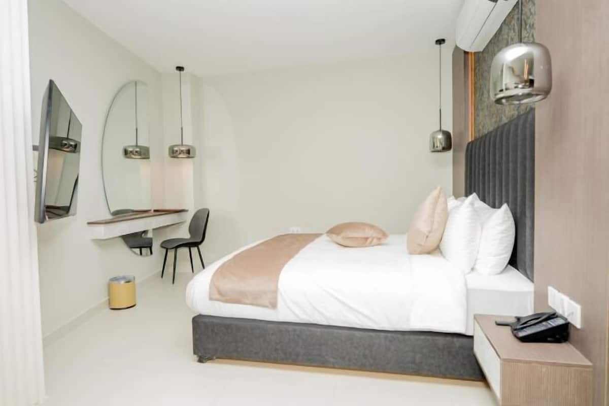A modern bedroom with a bed, bedside table, chair, and a desk with a chair.