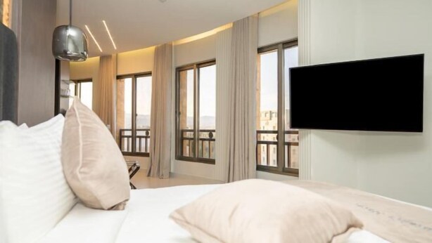 A hotel room with a large bed, a flat-screen TV mounted on the wall, and a balcony with a view. - Captain's Hotel (Aqaba)