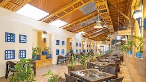 A restaurant with wooden ceiling beams, potted plants, and tables with chairs. - Captain's Hotel (Aqaba)