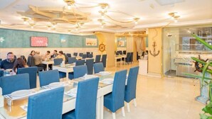 A restaurant with blue chairs, white tables, and a nautical theme including a ship's wheel and anchor decor. - Captain's Hotel (Aqaba)